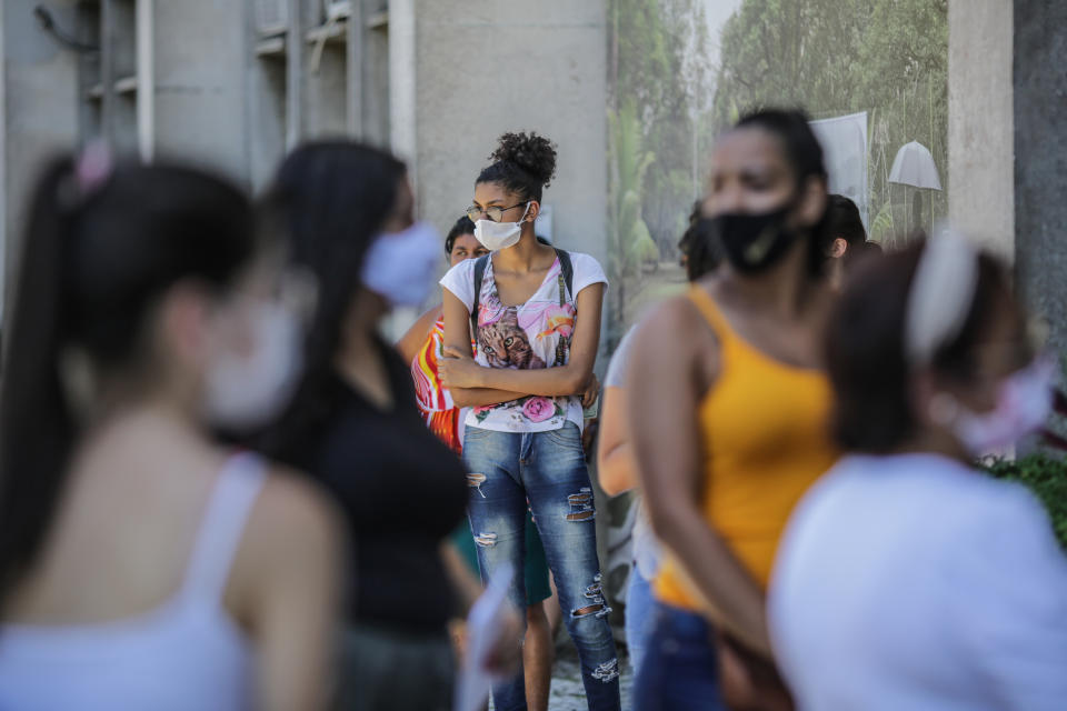 RIO DE JANEIRO, BRAZIL - JANUARY 17:  Students wearing protective masks wait in line at the Rio de Janeiro State University (UERJ) for the National High School Exam (ENEM) on January 17, 2021 in Rio de Janeiro, Brazil. Despite 15 Brazilian states showing an increase in the number of deaths from Coronavirus (Covid-19), the government maintained the exam and 5.7 million candidates are confirmed.  (Photo by Andre Coelho/Getty Images)