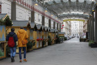 Two people walk by closed Christmas markets and shops due to the lockdown in Vienna, Austria, Tuesday, Nov. 30, 2021. (AP Photo/Lisa Leutner)