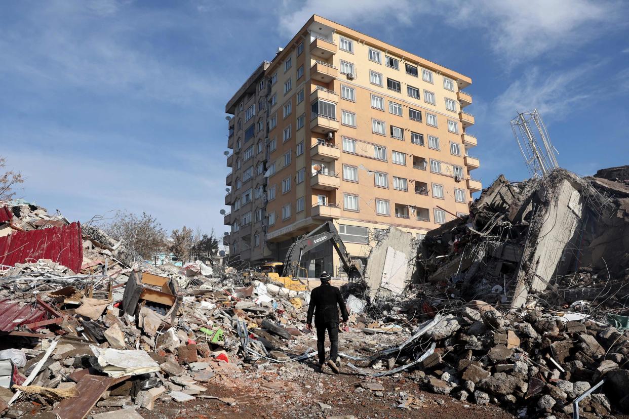 A man walks across the rubble of collapsed building towards a building still standing in Kahramanmaras (AFP/Getty)