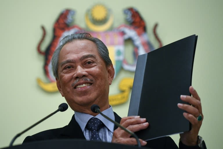 Malaysia&#39;s Prime Minister Muhyiddin Yassin holds a folder after unveiling his new cabinet