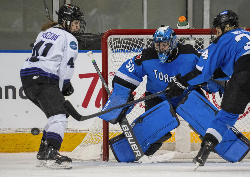 Toronto goaltender Kristen Campbell (50) keeps an eye on the action as Toronto forward Hannah Miller (34) battles Minnesota forward Denisa Krizova (41) during the second period of a PWHL hockey game in Toronto on Wednesday May 1, 2024. (Frank Gunn/The Canadian Press via AP)