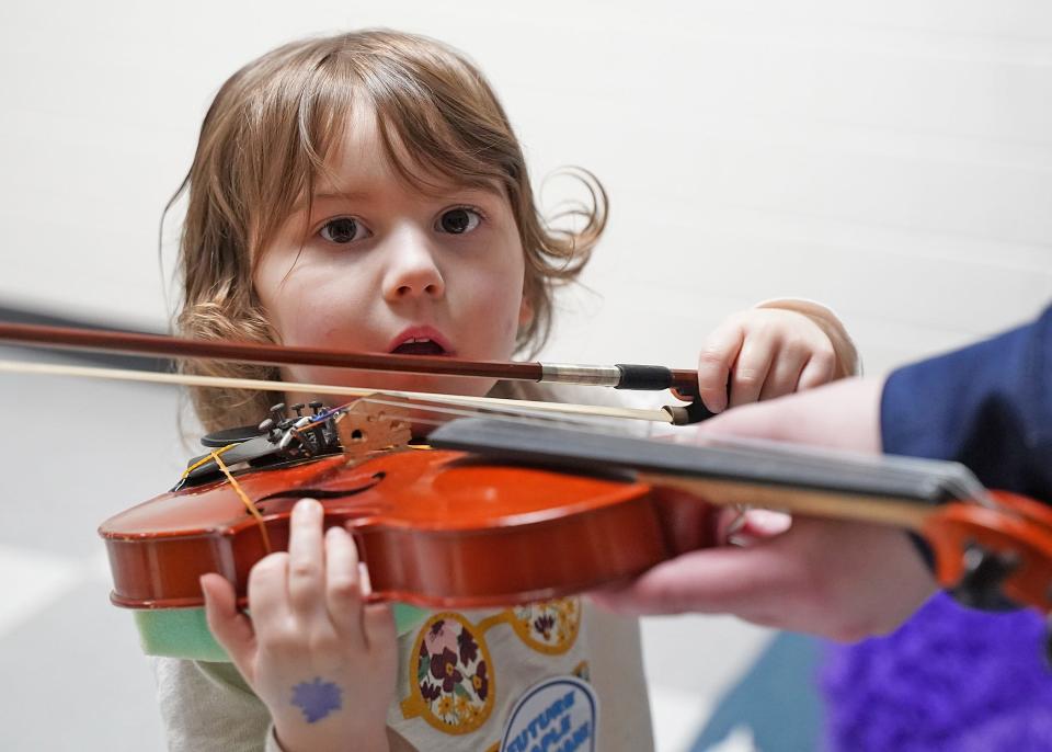 Ava Rumsey, 3, of Adrian plays a violin while participating in a kindergarten expo event Tuesday at Adrian High School.