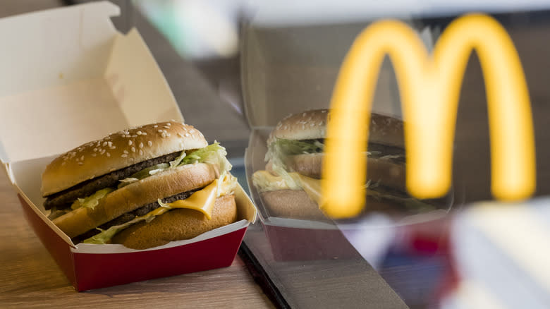 McDonald's Big Mac next to window with 'M' reflection