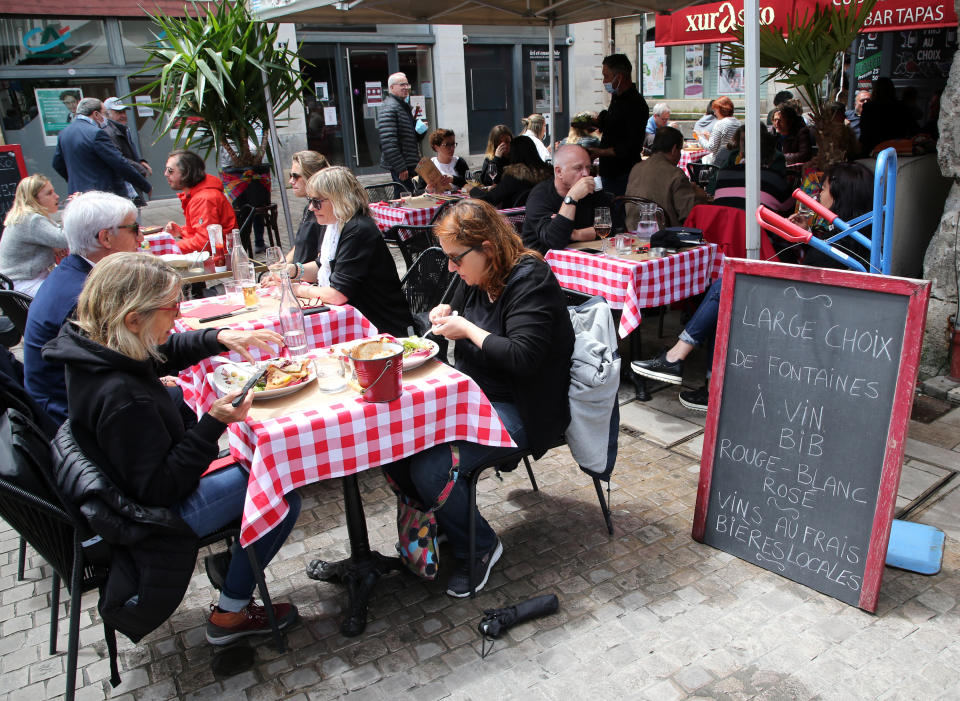 People enjoy a meal at a restaurant terrace Wednesday, May, 19, 2021 in Bayonne, southwestern France. Cafe and restaurant terraces reopened Wednesday after a six-month coronavirus shutdown. (AP Photo/Bob Edme)
