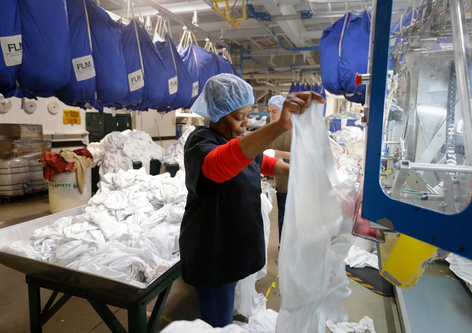 A worker places damp sheets on a drying and folding machine at  The Evergreen Cooperative Laundry in Cleveland.