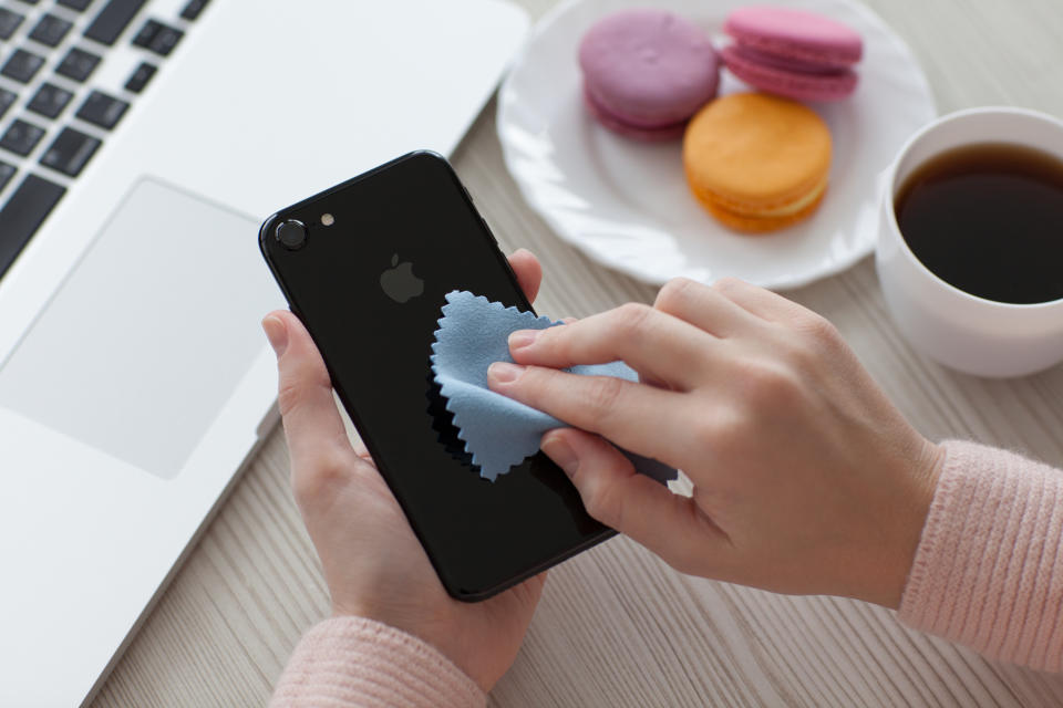 Alushta, Russia - November 19, 2016: Woman hand holding iPhone 7 and cleaning it. iPhone 7 Jet Black was created and developed by the Apple inc.