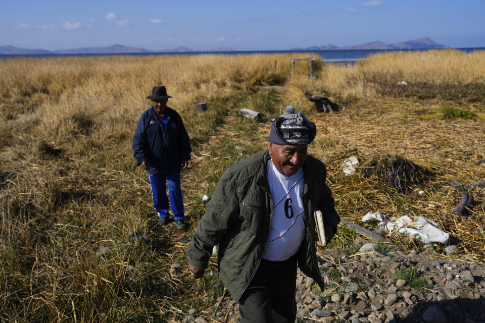 Fernando Huallapaco, al frente, y su hermano Francisco caminan donde solía haber agua a orillas del lago Titicaca en Huatajata, Bolivia, el viernes 29 de septiembre de 2023. (AP Foto/Juan Karita)