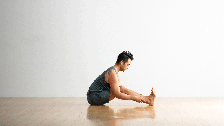 Man sitting and stretching tight hamstrings and low back with legs bent while leaning forward