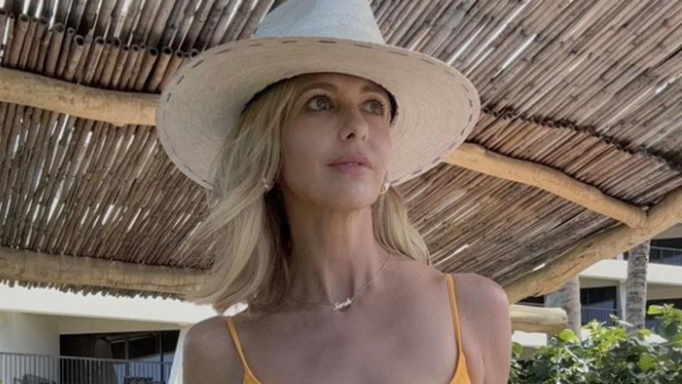 Sarah Michelle Gellar in an orange swimsuit and beige sunhat