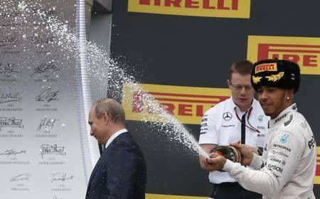 Russian President Vladimir Putin (L) leaves the winners podium as Mercedes Formula One driver Lewis Hamilton of Britain (R) sprays champagne in celebration after winning the Russian F1 Grand Prix in Sochi, Russia, October 11, 2015. REUTERS/Grigory Dukor