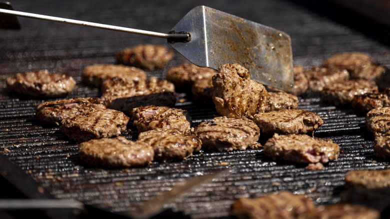 burgers on grill with spatula