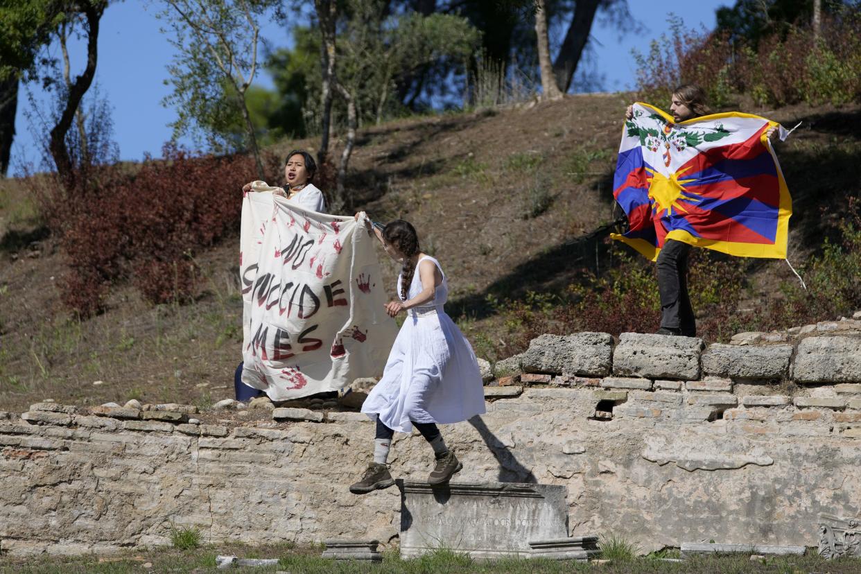 Protesters displaying a Tibetan flag and a banner reading "No genocide games" enter the grounds during the lighting of the Olympic flame at Ancient Olympia site, birthplace of the ancient Olympics in southwestern Greece, Monday, Oct. 18, 2021. 