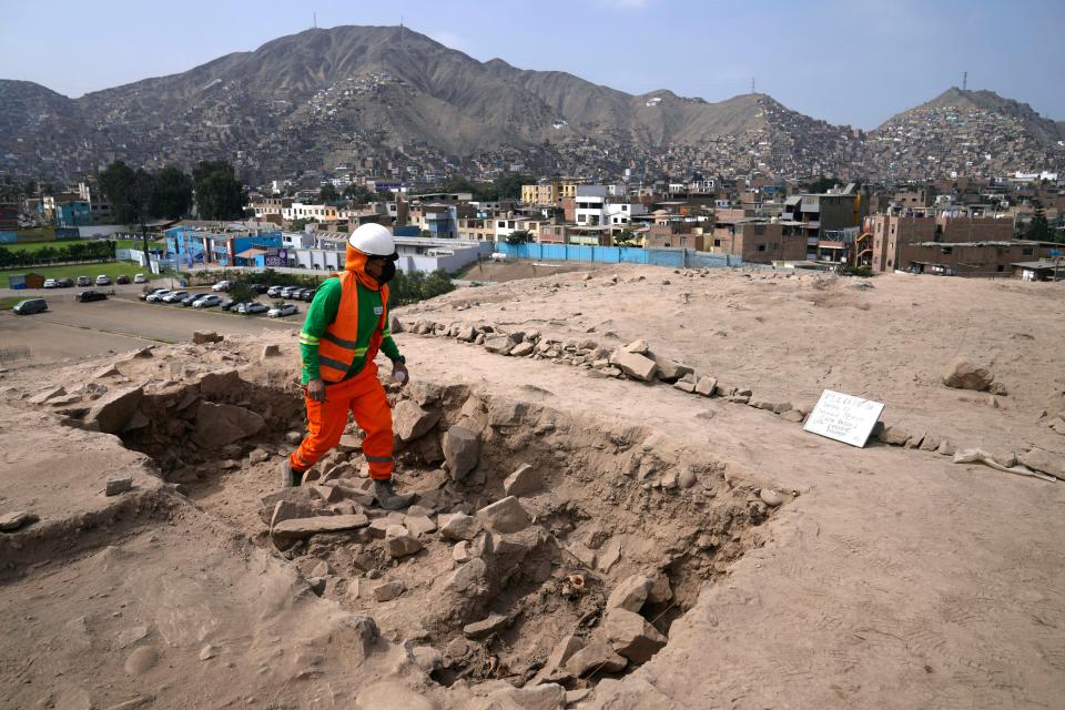 An archaeologist walks amid the remains of a pre-Hispanic mummy that was discovered next to a training field for a Peruvian professional soccer team in the El Rimac neighborhood of Lima, Peru, Thursday, June 15, 2023. (AP Photo/Martin Mejia)