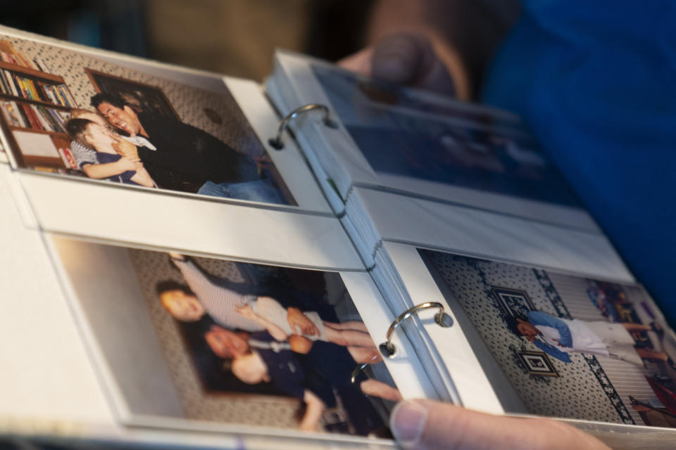 John Reynolds looks through old photographs of his family with minor league baseball players from the Johnson City Cardinals Thursday, April 27, 2023, in Johnson City, Tenn. The Reynolds hosted over 40 minor league baseball players from the Cardinals in their home for more than 10 years. (AP Photo/George Walker IV)