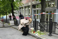 A woman lays flowers at the Ribnikar school in Belgrade, Serbia, Wednesday, May 3, 2023. Police say a 13-year-old who opened fire at his school drew sketches of classrooms and made a list of people he intended to target. He killed eight fellow students and a school guard before being arrested Wednesday. (AP Photo/Darko Vojinovic)