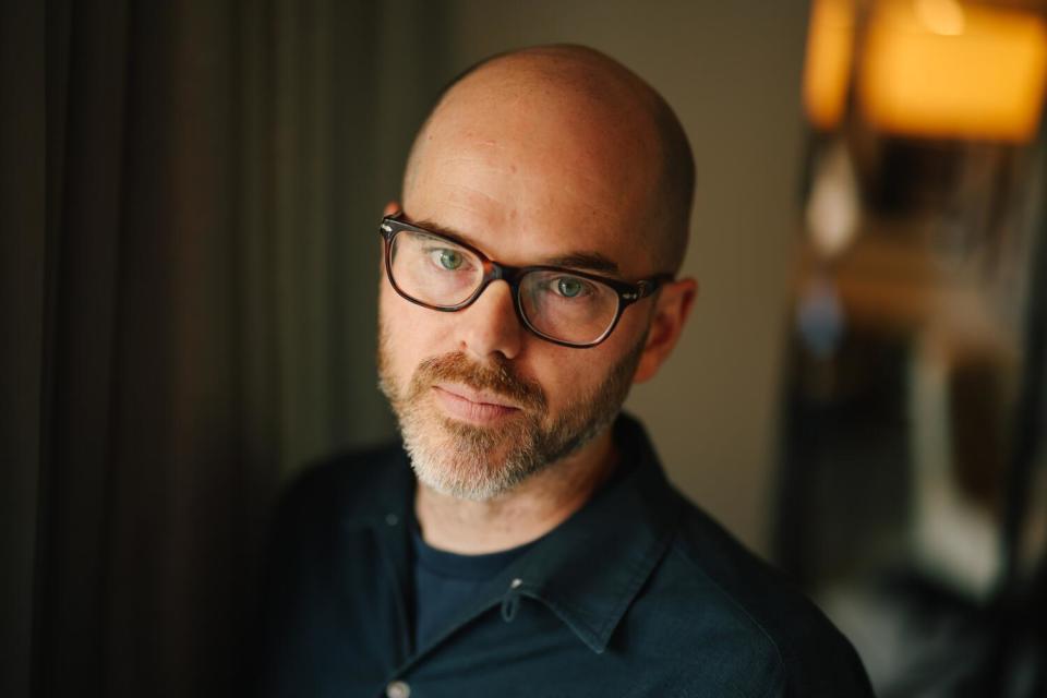 A man in glasses and a trimmed beard poses for the camera.