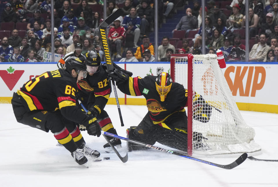 Vancouver Canucks goalie Casey DeSmith (29) looks for the puck after stopping Minnesota Wild's Marcus Johansson, not seen, as Canucks' Ilya Mikheyev (65) and Ian Cole (82) defend during the first period of an NHL hockey game Thursday, Dec. 7, 2023, in Vancouver, British Columbia. (Darryl Dyck/The Canadian Press via AP)