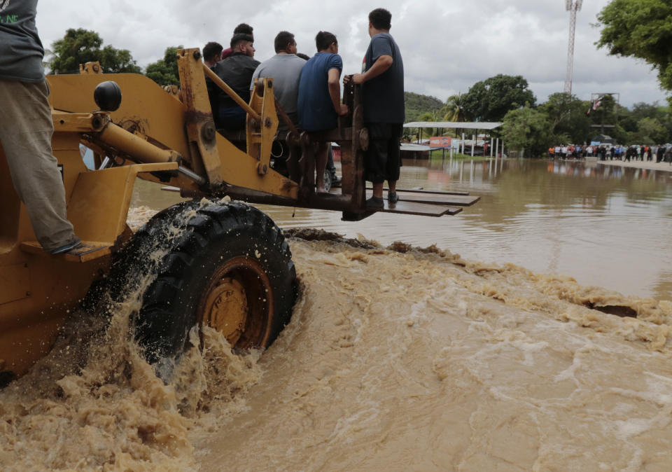 A heavy lifter carries people across a flooded area after the passing of Hurricane Iota in La Lima, Honduras, Wednesday, Nov. 18, 2020. Iota flooded stretches of Honduras still underwater from Hurricane Eta, after it hit Nicaragua Monday evening as a Category 4 hurricane and weakened as it moved across Central America, dissipating over El Salvador early Wednesday. (AP Photo/Delmer Martinez)