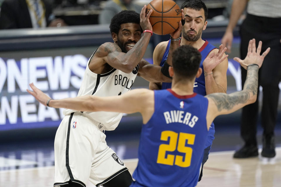 Brooklyn Nets guard Kyrie Irving is defended by Denver Nuggets guards Austin Rivers, front, and Facundo Campazzo during the second half of an NBA basketball game Saturday, May 8, 2021, in Denver. (AP Photo/David Zalubowski)