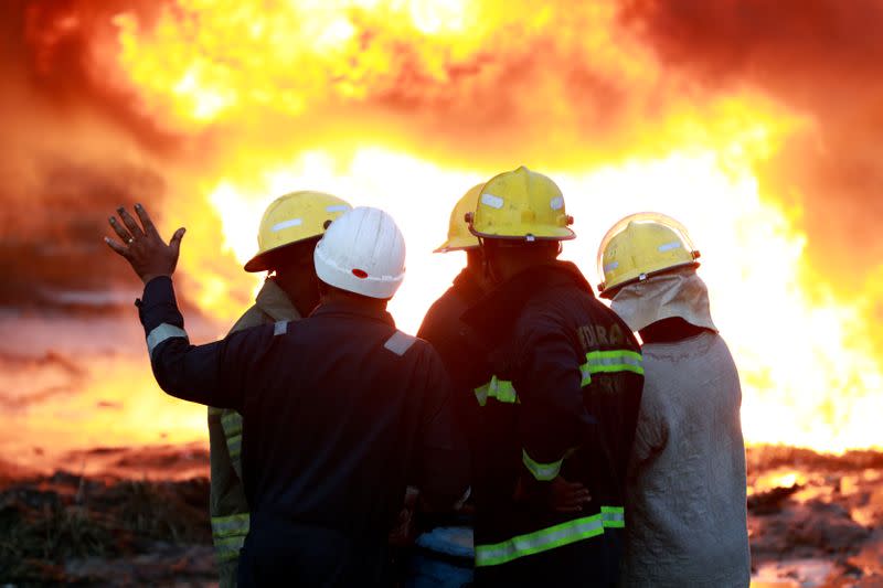 Firefighters deliberate on how to put out the fire as it continues to burn ata scene of the pipeline explosion at Abule-Ado in Lagos