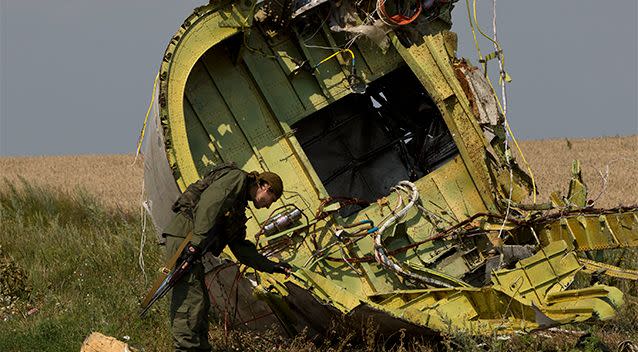 A pro-Russian rebel touches the MH17 wreckage at the crash site of Malaysia Airlines Flight 17, near the village of Hrabove, eastern Ukraine. Photo: AP.