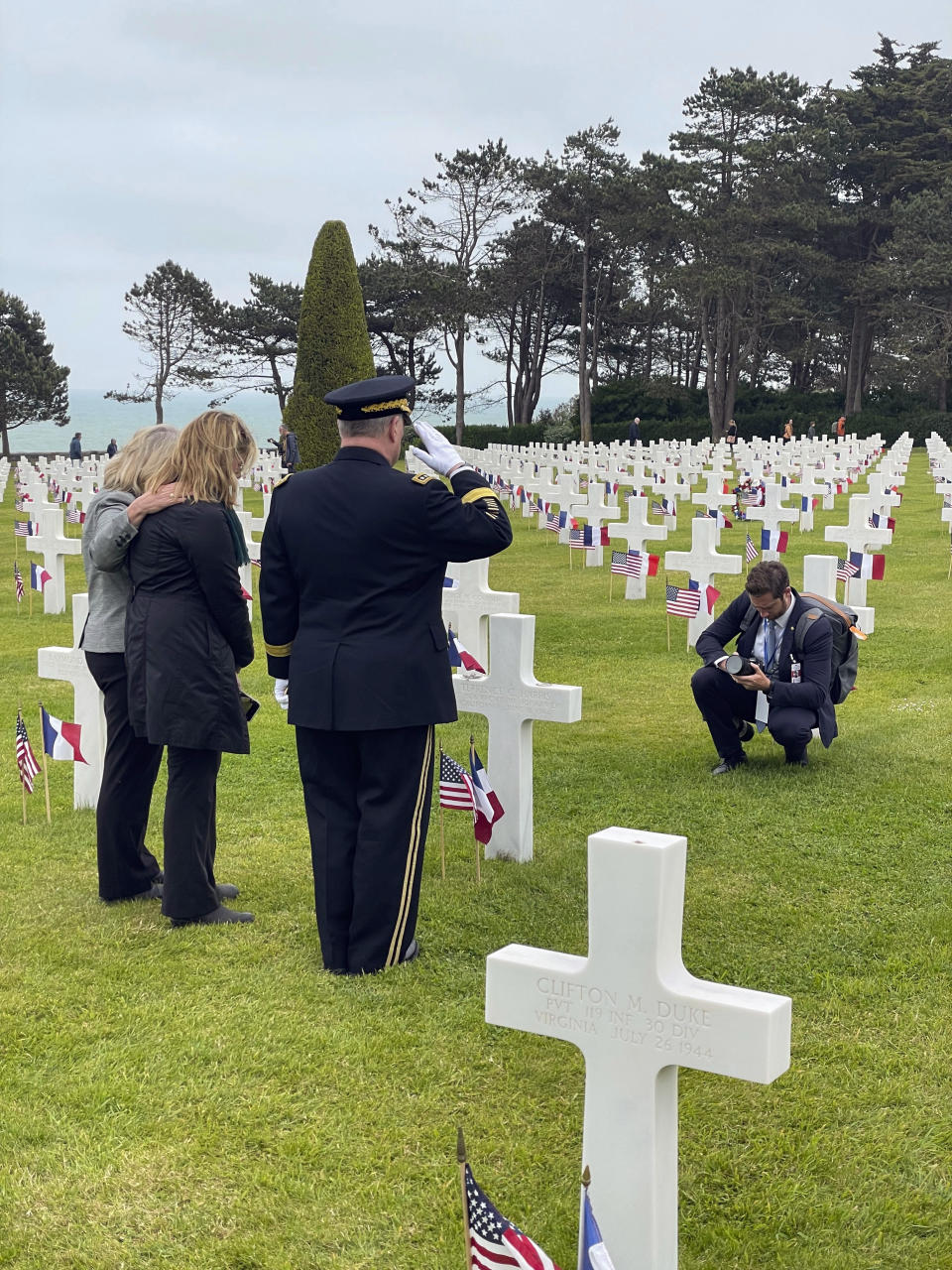 Associated Press reporter Tara Copp, second from left, stands with Joint Chiefs Chairman Gen. Mark Milley, third from left, and his wife Hollyanne, as they pause at the Normandy American Cemetery gravesite of Pfc. Terry Harris, Copp's great-uncle, in Colleville-sur-Mer, Normandy, France, June 6, 2023. Copp was covering Milley's last trip to Normandy as a U.S. soldier. Milley served in both airborne divisions who jumped into Normandy on June 6, 1944, and commanded the 506th Parachute Infantry Regiment, which was Harris' unit. (Oren Lieberman/CNN via AP)
