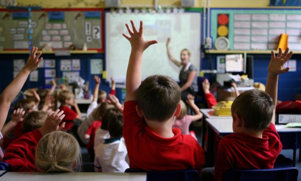 Children raising hands in classroom