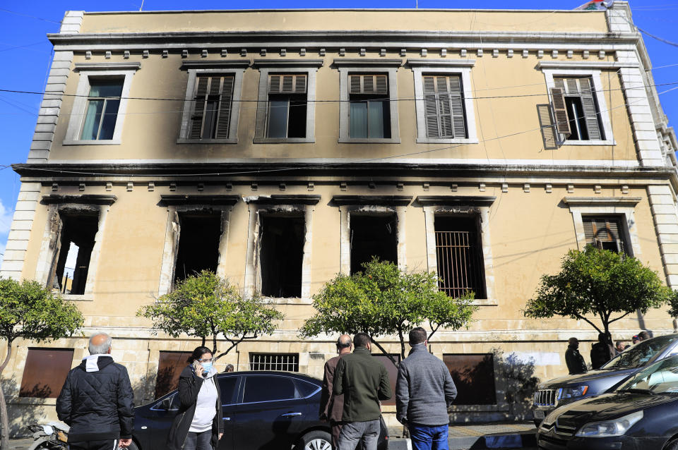 Lebanese people watch the damaged of Tripoli municipality building that was set on fire by protesters Thursday night, during a protest against deteriorating living conditions and strict coronavirus lockdown measures, in Tripoli, Lebanon, Friday, Jan. 29, 2021. (AP Photo/Hussein Malla)