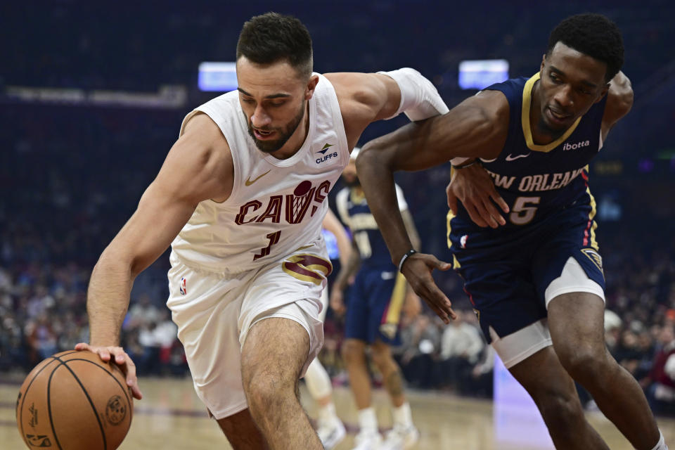 Cleveland Cavaliers guard Max Strus reaches for a rebound next to New Orleans Pelicans forward Herbert Jones during the first half of an NBA basketball game Thursday, Dec. 21, 2023, in Cleveland. (AP Photo/David Dermer)