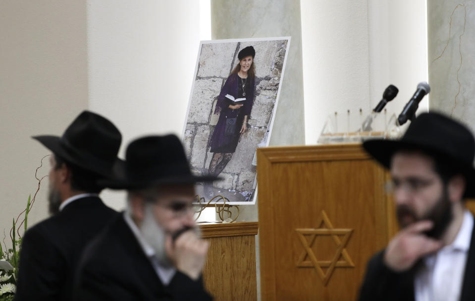 FILE - In this April 29, 2019, file photo, attendees at the funeral for Lori Kaye, who was killed when a gunman opened fire inside the Chabad of Poway synagogue in Poway, Calif., pass by a photo of Kaye inside the synagogue. (AP Photo/Gregory Bull, File)