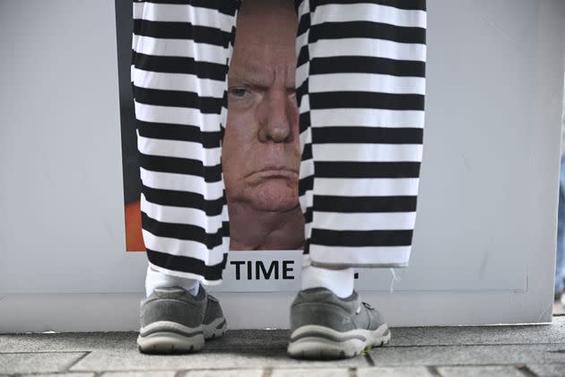 A protester holds a sign with an image of Trump outside the courthouse.