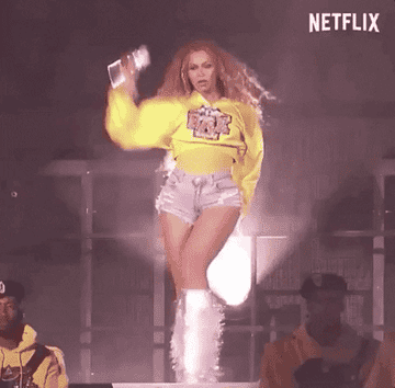 Beyoncé performs energetically on stage, wearing a yellow sweatshirt and denim shorts, accompanied by backup dancers. The Netflix logo is visible in the corner