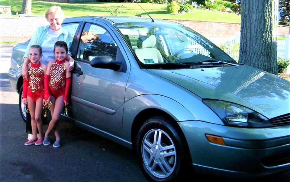 Mary Montminy, center, of Quincy at age 82 with her twin granddaughters, Julie, left, and Jackie  Montminy, right, age seven, in 2004 with Mary's brand new Ford Focus, She gave the car to the girls 11 years later when they got their licenses in high school and  she decided to give up driving at age 93. Julie still drives the car with 60,000 miles  at age 26.