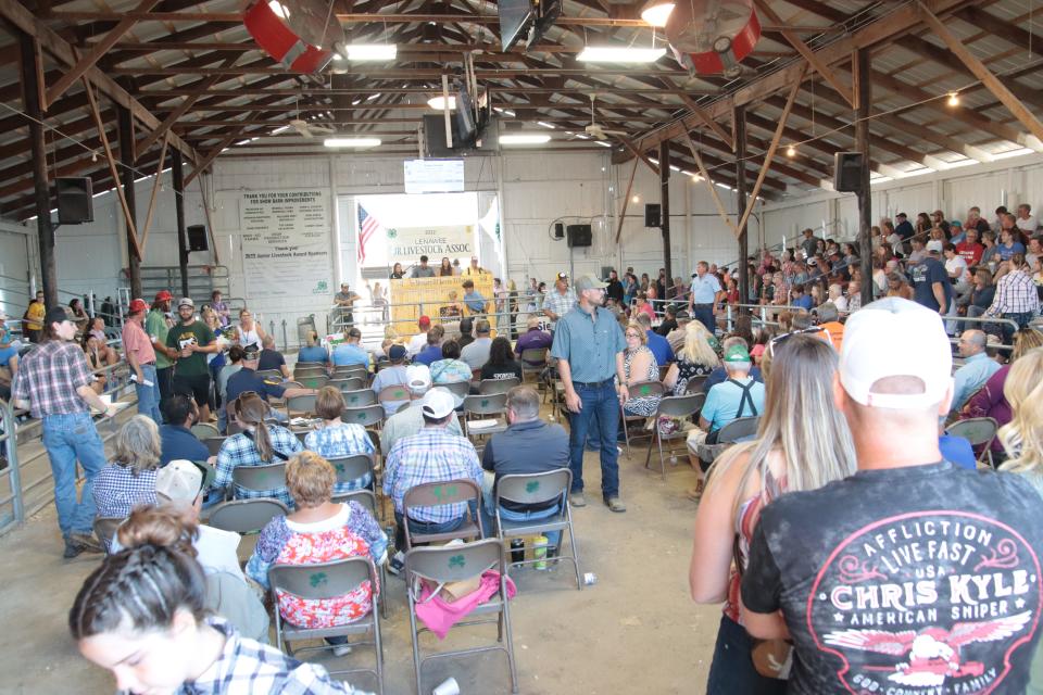 Assistants watch for auction bids at the 4-H show barn Friday at the Lenawee County Fair.