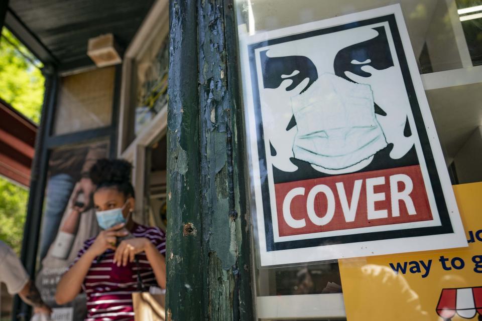 FILE - This Friday May 14, 2021 file photo shows a customer exiting a corner market while wearing a protective mask in the retail shopping district of the SoHo neighborhood in Manhattan borough of New York.. New York is seeing signs that more people are testing positive for the coronavirus, a contrast from weeks of declining rates of new positive tests. (AP Photo/John Minchillo, File)