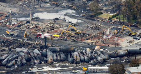 FILE PHOTO: Workers and firefighters work on the remains of downtown after a runaway train carrying crude oil derailed and exploded in Lac Megantic, Quebec, Canada, July 8, 2013. REUTERS/Mathieu Belanger/File Photo