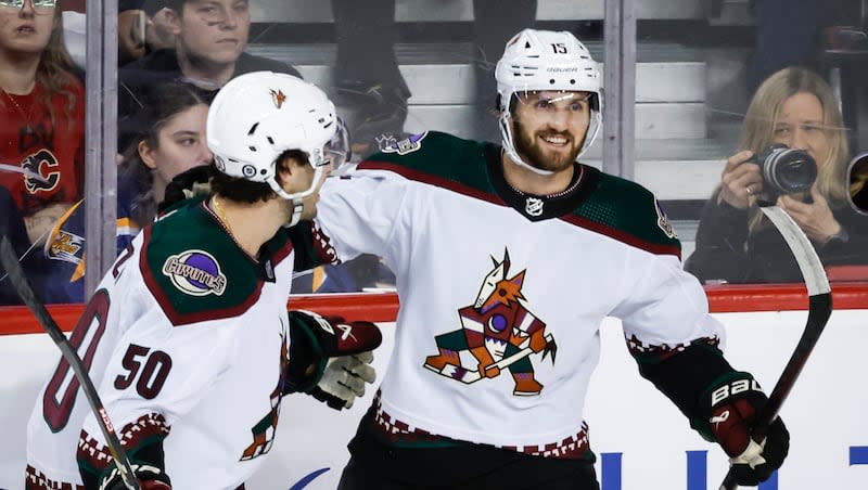 Arizona Coyotes forward Alex Kerfoot (15) celebrates his goal with teammate defenseman Sean Durzi (50) during the first period of an NHL hockey game against the Calgary Flames in Calgary, Alberta, Sunday, April 14, 2024.