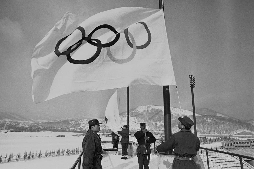 FILE - Members of Japan's self-defense ground forces raise Olympic flags in Sapporo, Japan, at Makomanai speed skating stadium in rehearsal of ceremony at official opening of Winter Olympic. on Jan. 23, 1972. (AP Photo, File)