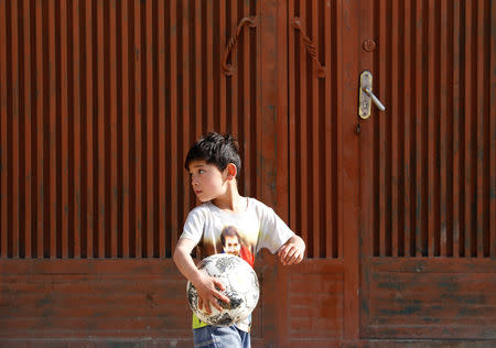 Murtaza Ahmadi, 7, an Afghan Lionel Messi fan, holds a ball outside his house in Kabul, Afghanistan December 8, 2018. REUTERS/Mohammad Ismail