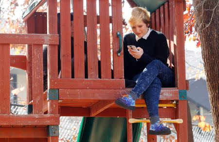 Student Rowan Brothers checks her phone during lunch outside in a treehouse at the Pride School in Atlanta, Georgia, U.S. on December 7, 2016. REUTERS/Tami Chappell