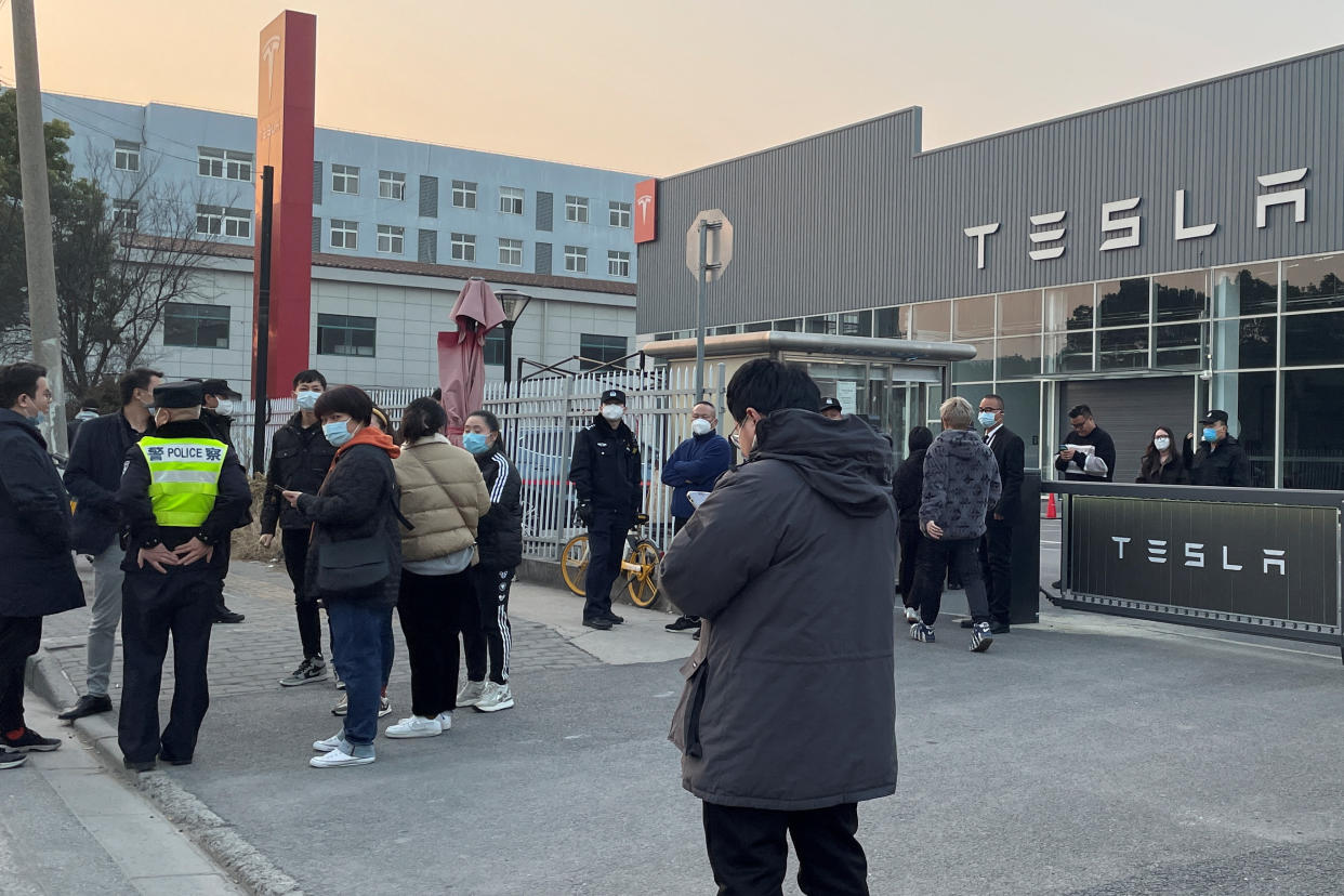 People walk out from a building as police officer stands near the entrance, after demonstrating at the Tesla delivery centre in Shanghai, China January 7, 2023. REUTERS/Brenda Goh