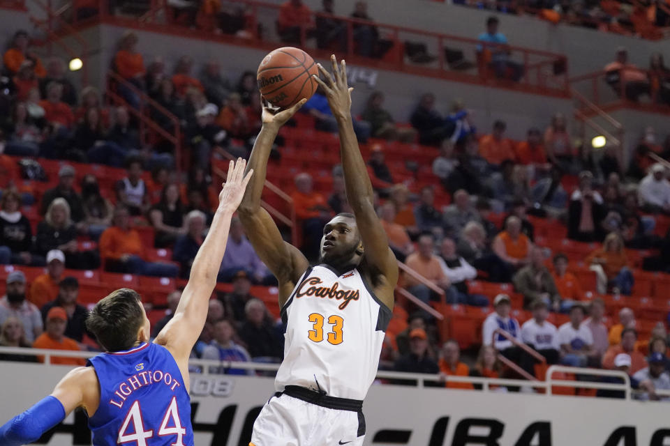 Oklahoma State forward Moussa Cisse (33) shoots over Kansas forward Mitch Lightfoot (44) in the first half of an NCAA college basketball game Tuesday, Jan. 4, 2022, in Stillwater, Okla. (AP Photo/Sue Ogrocki)