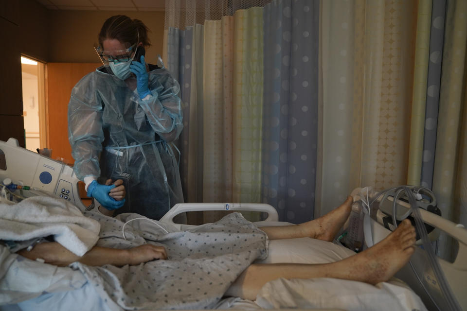 Chaplain Kristin Michealsen holds the hand of a deceased COVID-19 patient while talking on the phone with the patient's family member at Providence Holy Cross Medical Center in the Mission Hills section of Los Angeles on Saturday, Jan. 9, 2021. "I have never seen this much of death and suffering," said Michealsen, who has been a chaplain for 13 years. "I often tell families that I'm holding their loved one's hand when they can't and that I am with them when they are dying when they can't be." (AP Photo/Jae C. Hong)