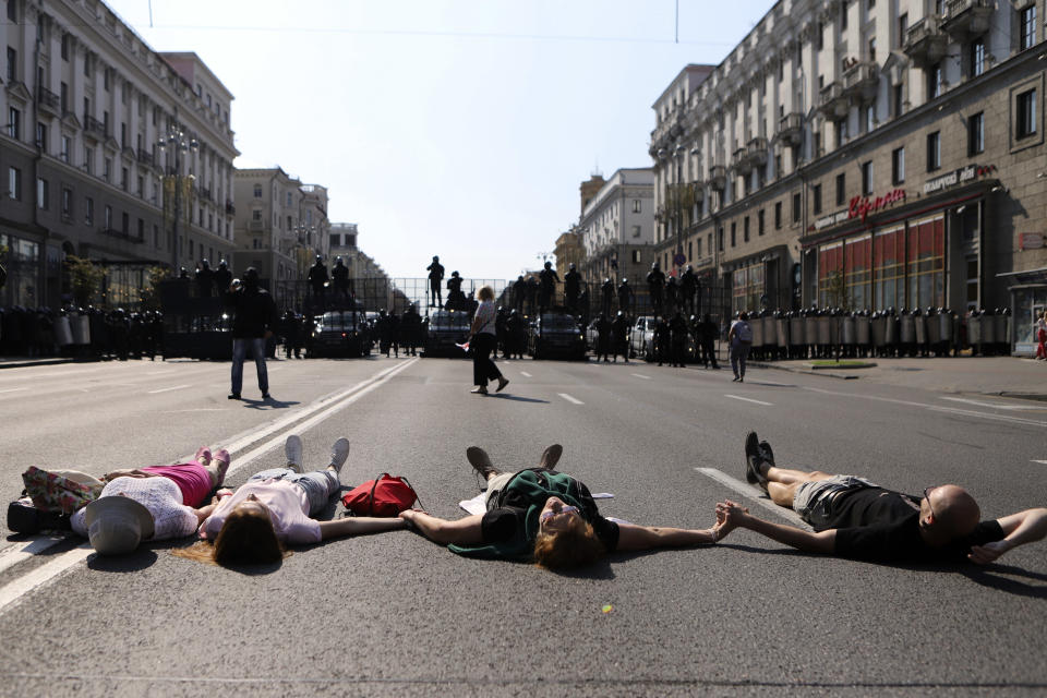 Protesters lie on the ground in front of riot police line blocking Belarusian opposition supporters rally in the center of Minsk, Belarus, Sunday, Aug. 30, 2020. Opposition supporters whose protests have convulsed the country for two weeks aim to hold a march in the capital of Belarus. (AP Photo)