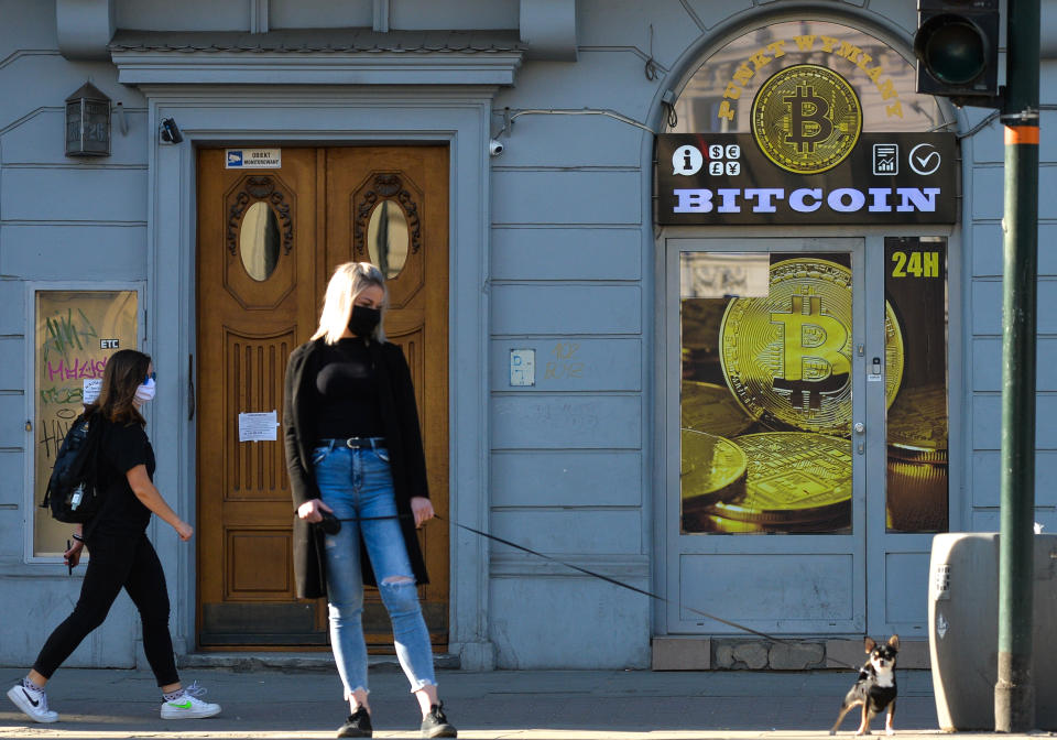 A lady wearing a protective mask walks her dog in front of a Bitcoin exchange shop in Krakow's city center.  On Saturday, April 18, 2020, in Krakow, Poland. (Photo by Artur Widak/NurPhoto via Getty Images)