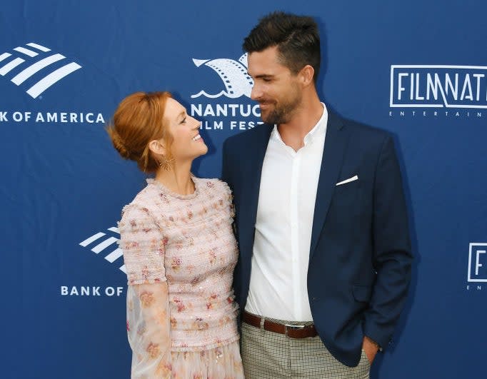 Brittany in beaded dress smiling at Tyler in blazer and patterned trousers at a media event