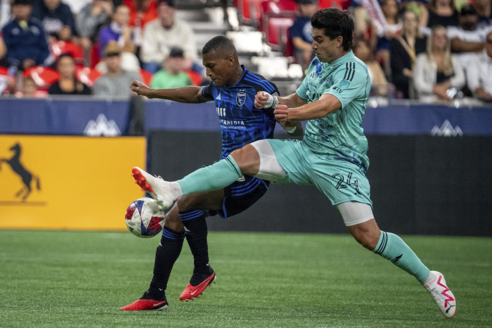 Vancouver Whitecaps' Brian White (24) and San Jose Earthquakes midfielder Carlos Gruezo, left, battle for control of the ball during first-half MLS soccer match action in Vancouver, British Columbia, Sunday, Aug. 20, 2023. (Ethan Cairns/The Canadian Press via AP)