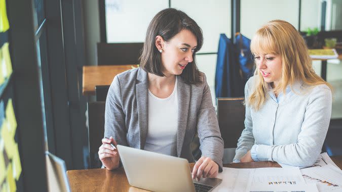 Two businesswoman working together with laptop and paperwork at coffee shop, color tone effect.