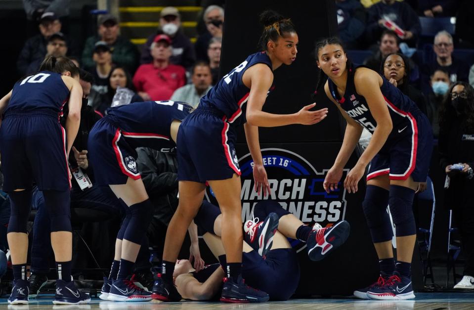UConn players surround Juhasz after she injured her wrist.