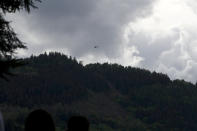 An helicopter flies over the cable car line that collapsed, near Stresa, Italy, Sunday, May 23, 2021. A cable car taking visitors to a mountaintop view of some of northern Italy's most picturesque lakes plummeted to the ground Sunday and then tumbled down the slope, killing at least 13 people and sending two children to the hospital, authorities said. (AP Photo/Antonio Calanni)